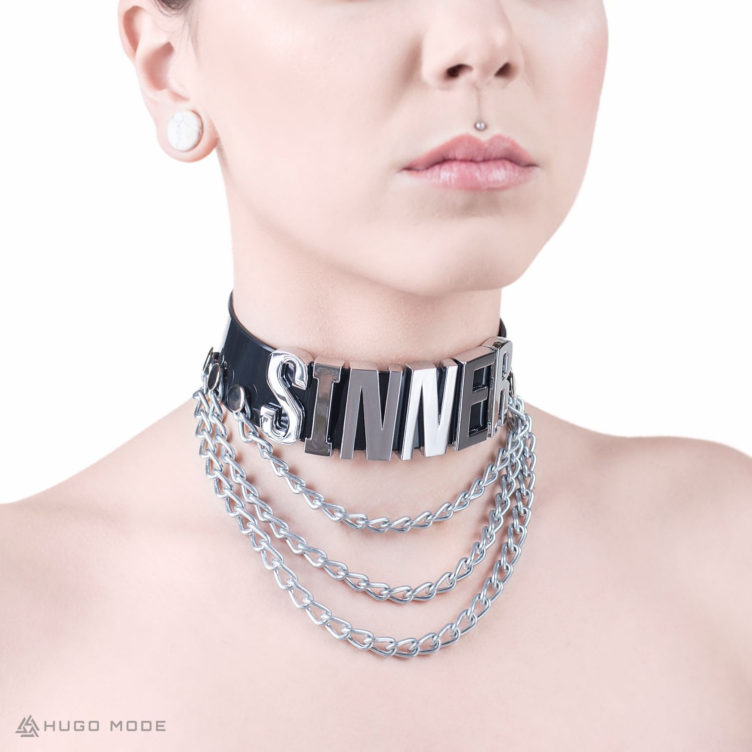 A wide neck choker decorated with chains and an inscription.