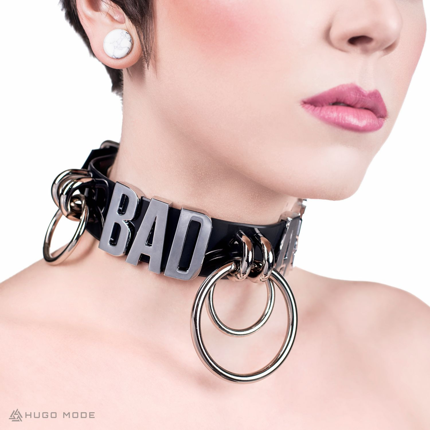 A choker necklace decorated with rings and the word BAD ASS.